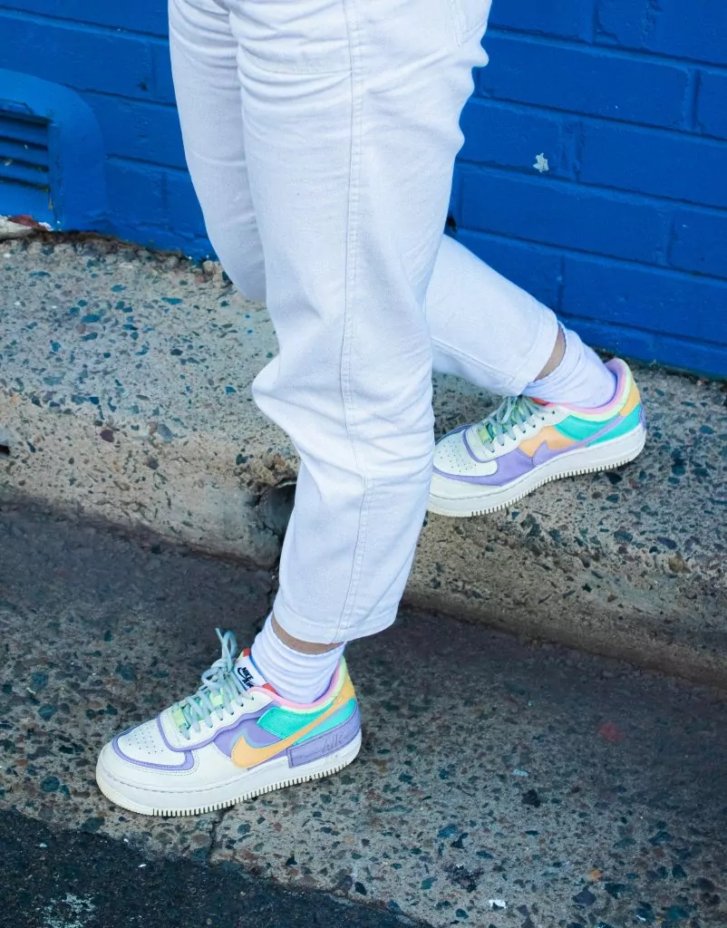 person in blue denim jeans and white green and pink nike sneakers
